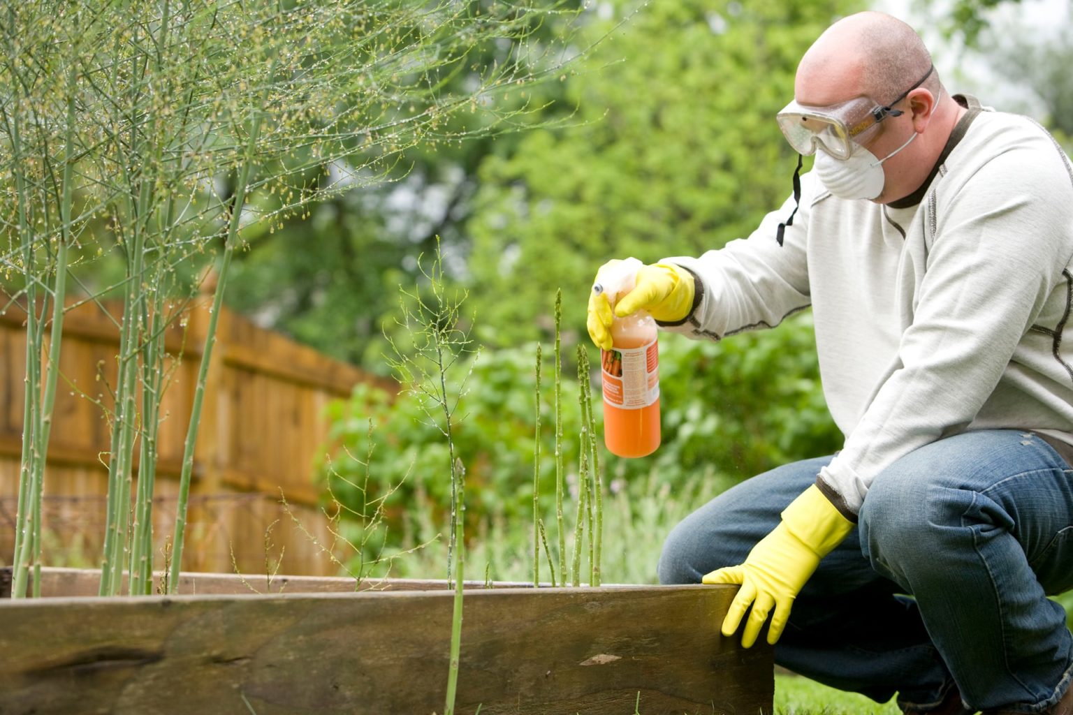 a man wearing gloves and a mask holding a bottle of liquid