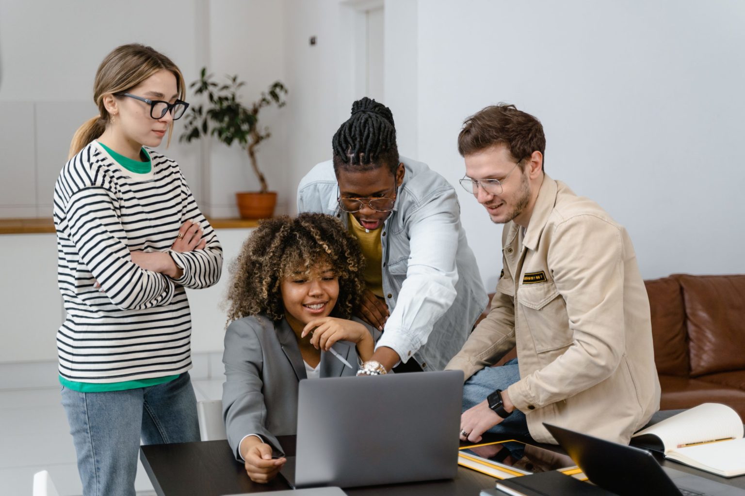 a group of people standing around a laptop