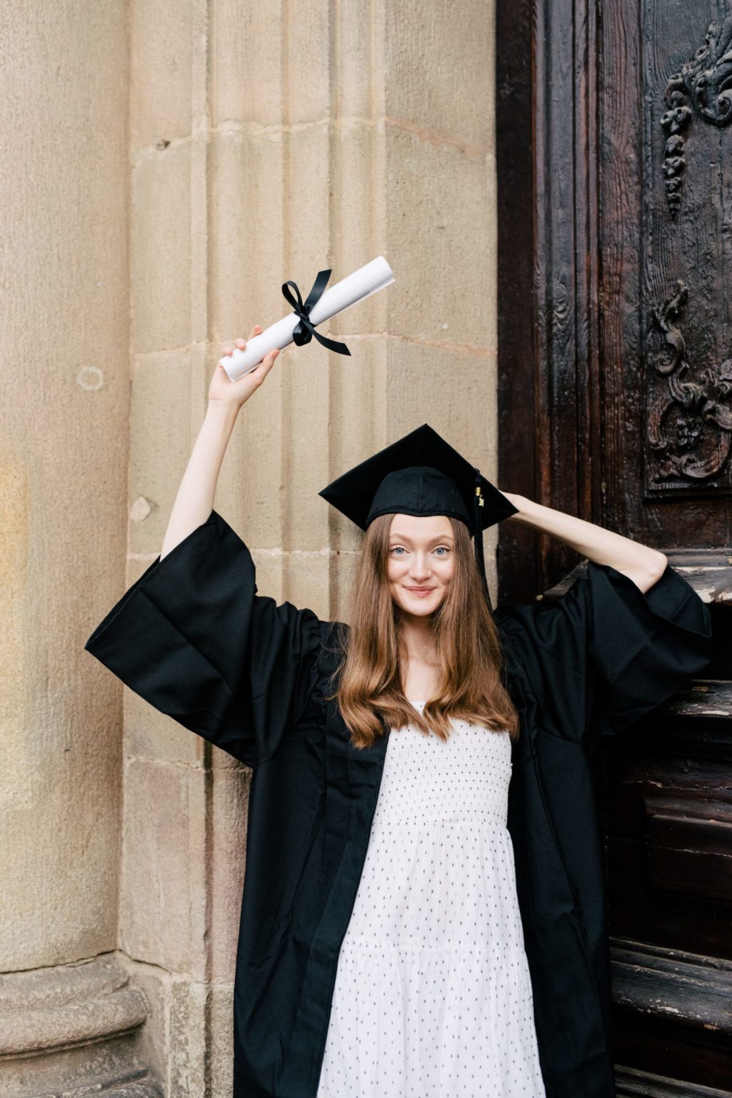 a person in a graduation gown and gown holding a diploma