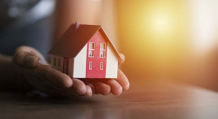 a hand holding a red house