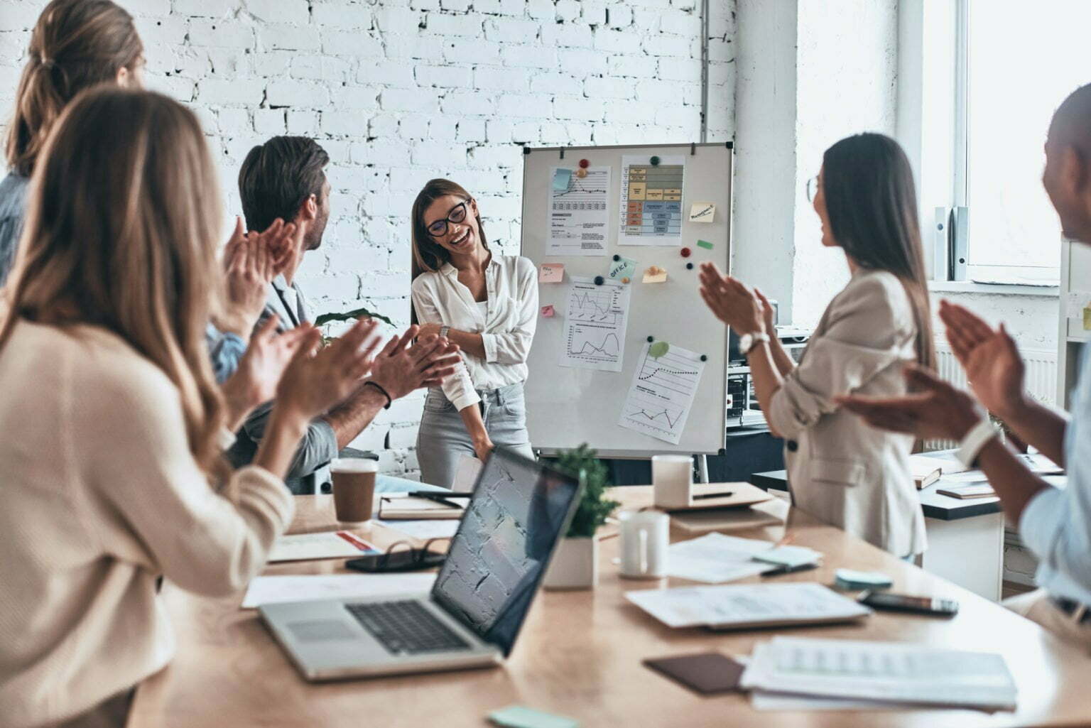 Great presentation. Group of business people clapping and smiling while standing in the board room